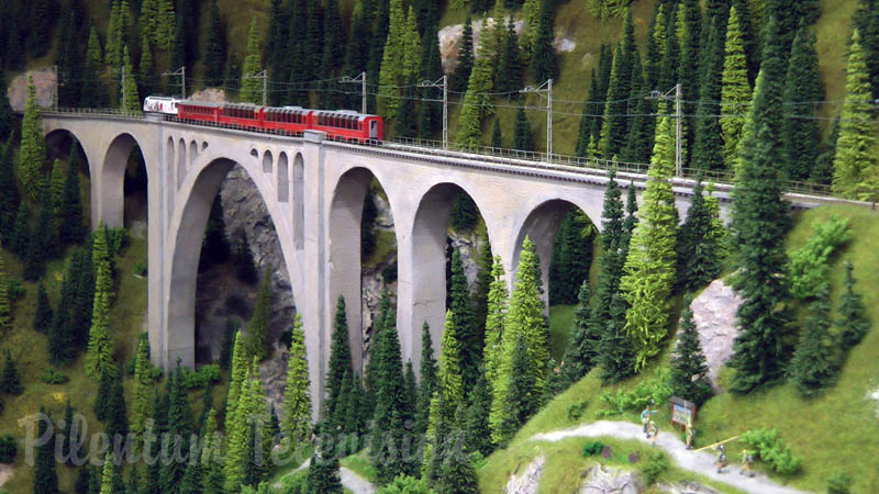 Modeltreinen uit Zwitserland steken de spoorwegbrug over op meterspoor