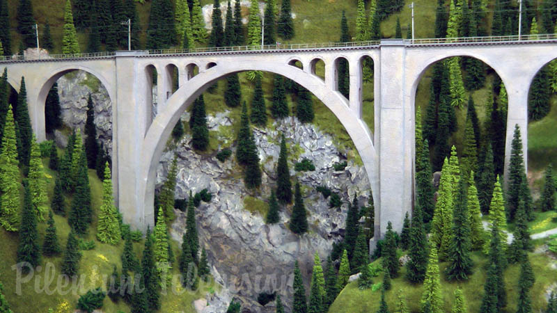 Trenes en miniatura de Suiza cruzando el puente del ferrocarril en el ancho de vía métrico