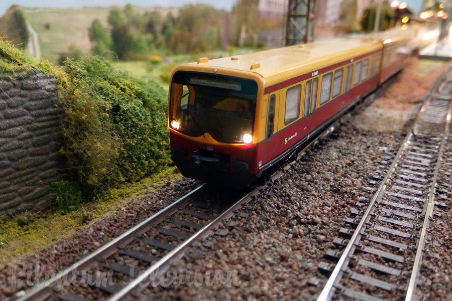 Model trains in action on a TT scale model railway layout with diesel and steam locomotives